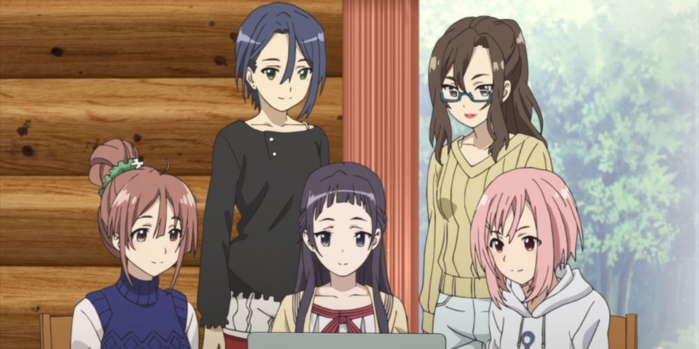 Maki, Sanae, Shiori, Ririko, and Yoshino sitting around a computer planning in Sakura Quest